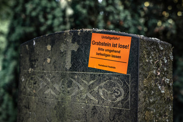 Gefahrenhinweis auf einem Grabstein auf einem historischen Friedhof (öffentlicher Park)