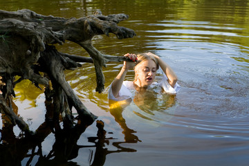 Fototapeta premium Beautiful girl in a white dress in the water.