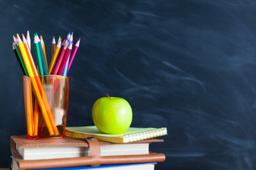 Back to School cocept. Still life with school books, pencils and apple against blackboard background - 218042900