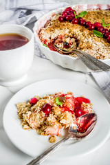 Traditional autumn winter pastries, homemade pie crumble with apples and cranberries, on a white marble table, copy space for text