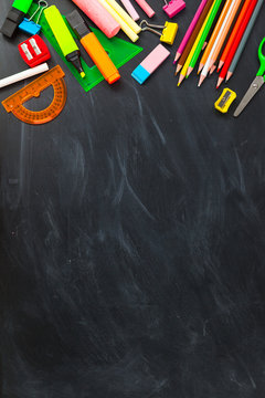 Back To School concept. School supplies on blackboard background, accessories for the schoolroom - pencils, notebooks, scissors, chalk, markers.