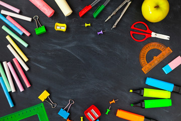 Back To School concept. School supplies on blackboard background, accessories for the schoolroom - pencils, notebooks, scissors, chalk, markers.