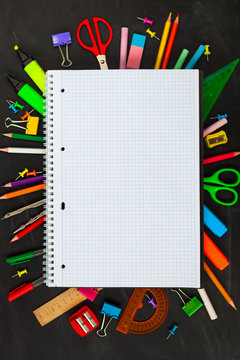 Back To School concept. School supplies on blackboard background, accessories for the schoolroom - pencils, notebooks, scissors, chalk, markers.