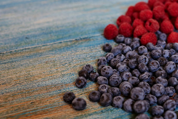 Berries on blue  background. Summer or spring organic berry.  Agriculture, gardening, harvest concept. Fresh sweet blueberry, raspberry fruit. Healthy food. Selective focus. Top view with copy space.