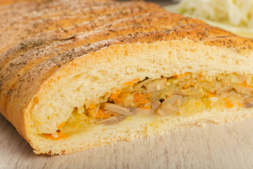 Pie with cabbage and mushrooms on a wooden background with ingredients.