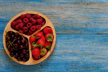 Ripe sweet different berries in bowl. Natural organic raspberries, strawberries and cherry. Close up, top view with copy space. Harvest concept.