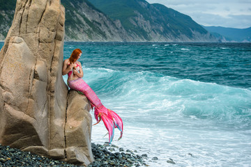 Beautiful mermaid with long tail on sea shore