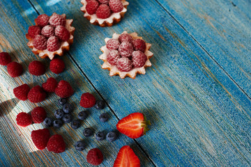 Cook Italian bakery prepare light mouth-watering diet of pastry tartlets with fresh raspberries, sprinkle them with powdered sugar