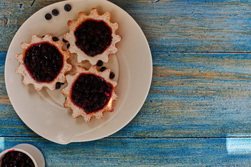 Top view of a housewife beautifully and carefully prepared it served dessert, small tartlets of shortcrust pastry with homemade jam from berries