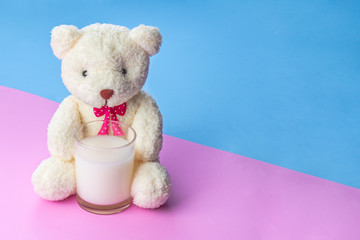 teddy bear holding a glass of milk on pink blue rubber foam sheet background