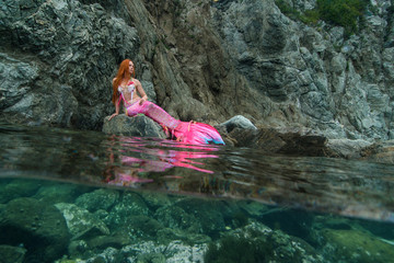 Beautiful mermaid with long tail on sea shore