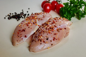 Raw uncooked chicken fillet on a cutting table with ingredients for cooking - garlic, pepper,...