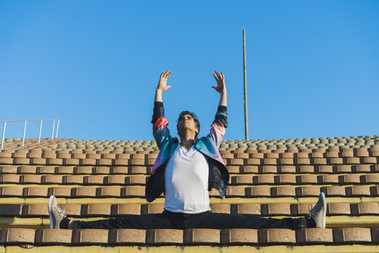 Man doing side splits on stairs of a stadium