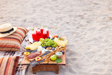 Pique-nique sur la plage au coucher du soleil dans le style bohème. Concept de dîner sain en plein air avec des fruits et des jus de fruits