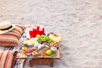 Foto op Plexiglas Picknick op het strand bij zonsondergang in de stijl van boho. Concept buiten & 39 s avonds gezond diner met fruit en sap © yatcenko