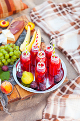 Picnic on the beach at sunset in the style of boho. Concept outdoors evening healthy dinnner with fruit and juice