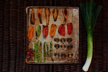 Baked crispy vegetables are served in the order on a baking sheet, lay on the right bunch of onions
