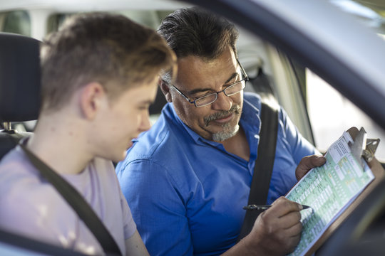 Learner driver with instructor in car looking at test script