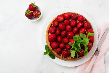 Cheesecake with fresh strawberries and mint on white plate on gray concrete background. Top view.