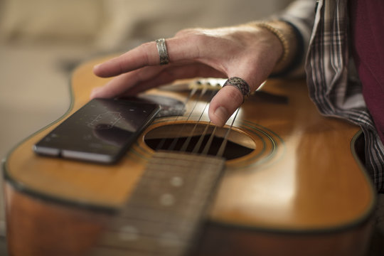 Close-up of man's hand, cell phone and guitar