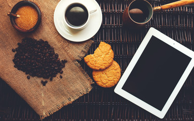 Top view on a wicker table is a plate, a small mug with aromatic coffee and homemade biscuits, coffee beans near rasspany better grades