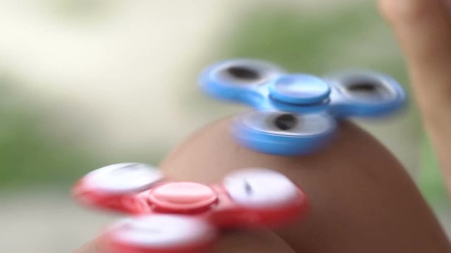 Girl Balancing Two Fidget Spinners On The Knees, Slow Motion.