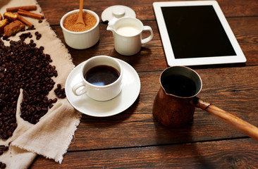 The stylish cafe on the table was served coffee, lying beside the plate, poured in a white cup of coffee standing next to the milk