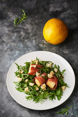 Concept of italian food with arugula, prosciutto, and melon salad