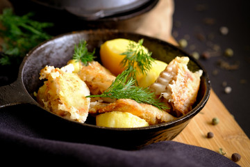 Potatoes and fish fried on a cast-iron frying pan