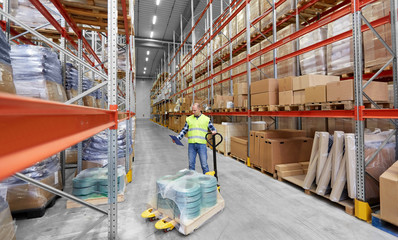 logistic business, shipment and loading concept - male worker with loader and clipboard at warehouse