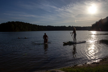 Stand up paddle boarding sup on a quiet lake with warm summer sunset colours