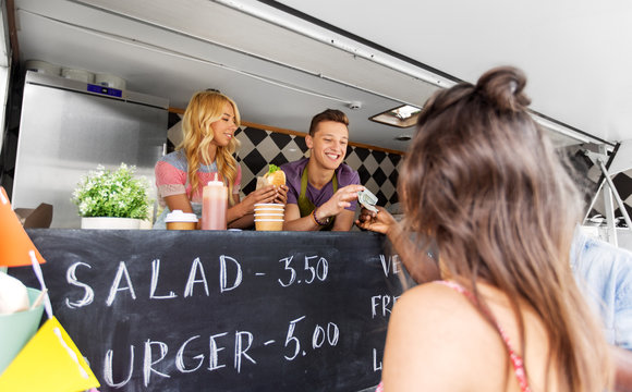 street sale, payment and people concept - happy customers buying burger at food truck