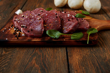 Close up of raw fresh meat ribeye steak with herbs and spices on dark rustic background. Healthy food concept.