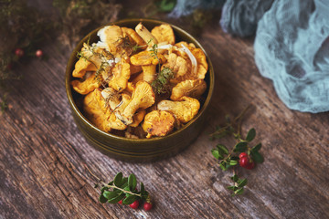 Raw wild mushrooms chanterelles in bowl on old wooden background.
