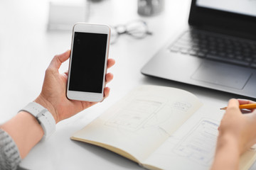 app design, technology and business concept - web designer or developer with smartphone working on user interface and drawing sketches at office