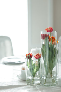The wedding table is decorated with vases of red and orange talpans