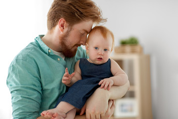 family, fatherhood and people concept - happy red haired father with little baby daughter at home