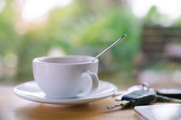 Cup of hot coffee Smart phone and car key on wood table.Selective focus
