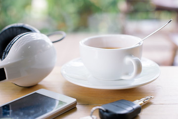 Cup of hot coffee Smart phone,car key and headphone on wood table.Selective focus