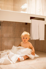 Toddler baby boy, ripping up with toilet paper in bathroom.