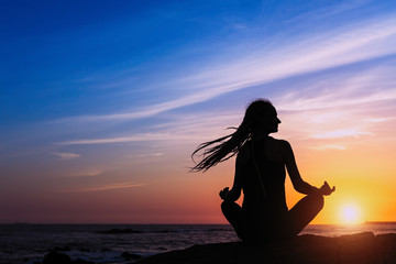 Fototapeta premium Yoga woman silhouette meditation on the ocean during amazing sunset. Healthy lifestyle.
