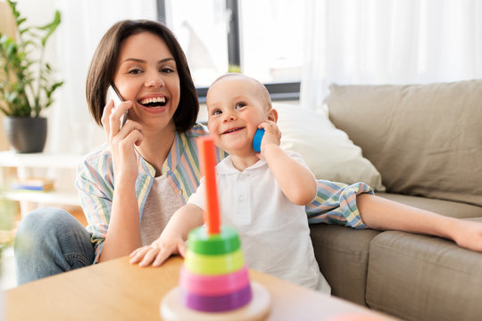family, child and motherhood concept - happy mother calling on smartphone and little baby boy playing developmental toy at home