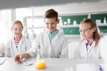 Fototapeta premium education, science, chemistry and children concept - kids or students with test tube making experiment at school laboratory