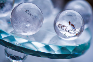 Macro shot of transparent crystal balls with colorful ornaments and sun reflections in it, on turquoise glass pad. Fortune telling. Love, money, luck, success.