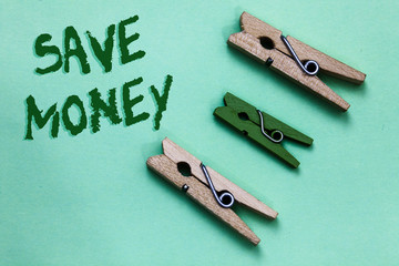 Text sign showing Save Money. Conceptual photo store some of your cash every month to use them sometime later Three brown green vintage clothespins clear background Holding things