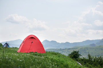 Tent is built in meadow. Beautiful, fresh morning in mountain landscape next to medieval village. Concept of freedom, camping and travelling around the world. Picnic in nature  