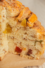 Cake with candied fruits in a cut on a wooden background.