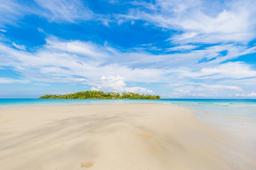 Fototapeta na wymiar Tropical empty tranquil white sand beach with green forest island