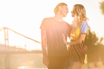 young couple hugging and going to kiss on river beach in evening