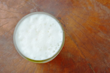 cold beer with frothy in glass on wooden background